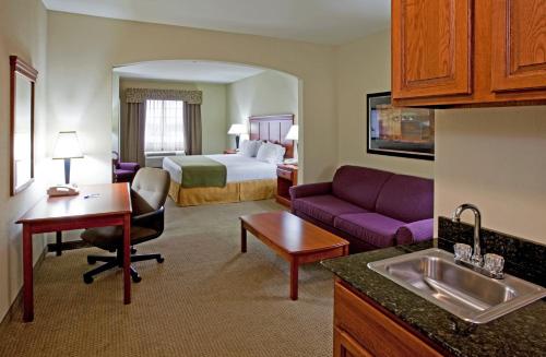 a hotel room with a bed and a living room at Holiday Inn Express Hotel and Suites Ada, an IHG Hotel in Ada