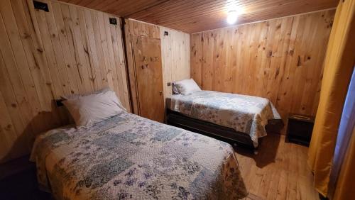 twee bedden in een kamer met houten wanden bij Cabaña Río Contao in Contao