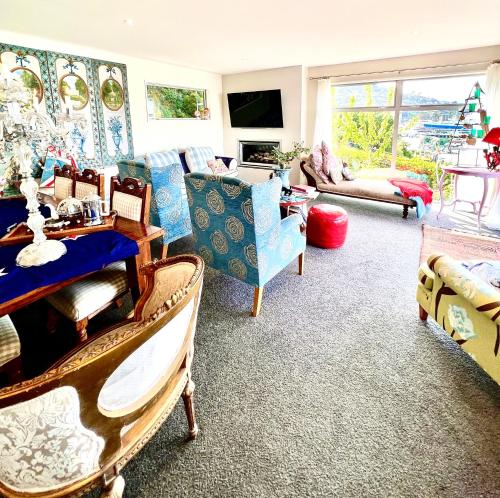 Sea views in luxury at LYTTELTON BOATIQUE HOUSE - 14 km from Christchurch في  Lyttelton: غرفة معيشة مع كراسي وطاولة وأريكة