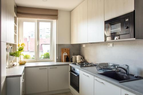 a kitchen with white cabinets and a sink at Light Room by Zoom Apartments in Bratislava