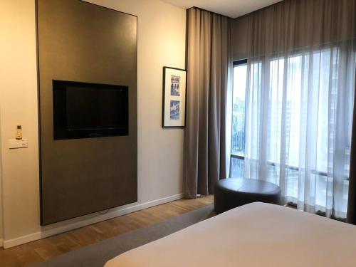 クアラルンプールにあるLarge 3-Bedroom Modern Resort Style KLCC Apartmentのベッド1台、薄型テレビが備わるホテルルームです。