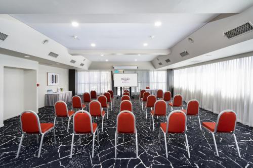 a conference room with red chairs and a podium at Mercure Rockhampton in Rockhampton