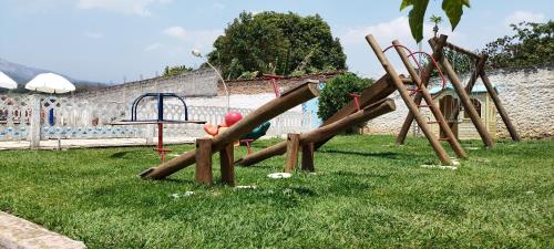 a group of wooden playground equipment in the grass at Chácara Sorriso 2 in Atibaia