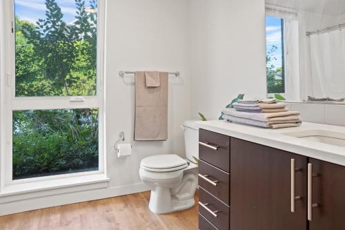 a bathroom with a toilet and a sink and a window at NEW Bright Capitol Hill Condo, Great Location Views in Seattle