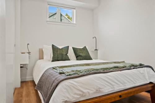 a white bedroom with a large bed with green pillows at NEW Bright Capitol Hill Condo, Great Location Views in Seattle