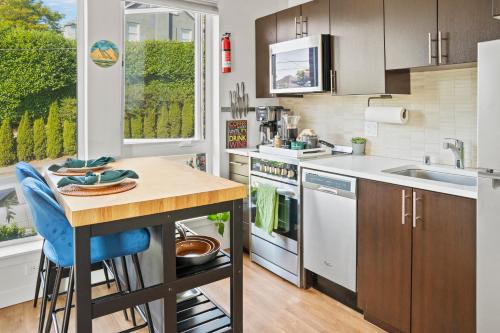 a kitchen with a counter and a table with blue chairs at NEW Bright Capitol Hill Condo, Great Location Views in Seattle