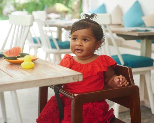 a little girl sitting in a chair at a table at Bliss Dhigurah in Dhigurah