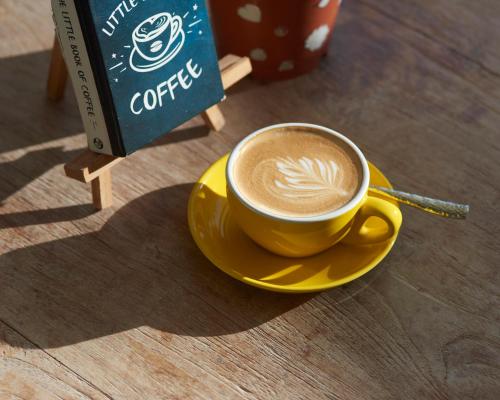 a cup of coffee on a yellow plate on a table at Bliss Dhigurah in Dhigurah