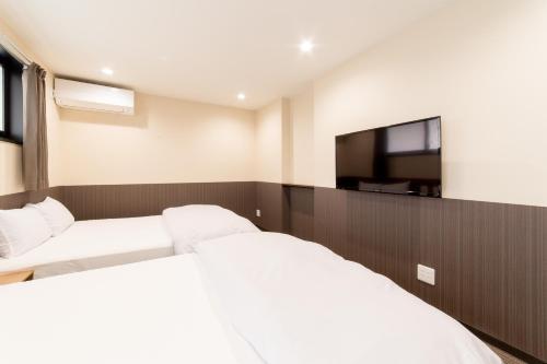 a bedroom with two beds and a flat screen tv at Le Studio 五条高倉 in Kyoto
