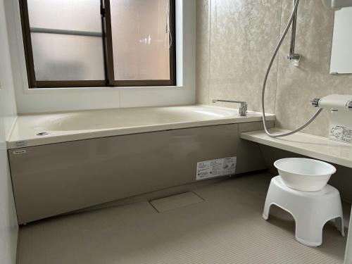 uma casa de banho com uma banheira, um WC e uma janela. em Ocean Hills Kouri em Nakijin