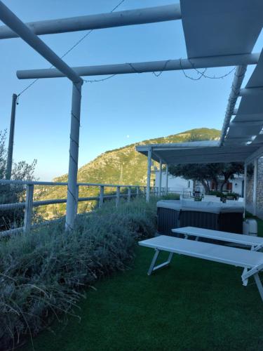 a picnic table under a pergola with a view of the ocean at Villa Cimea in Furore