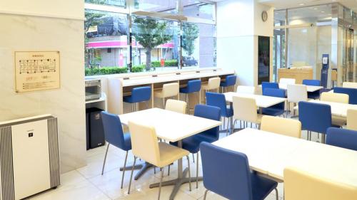 a restaurant with white tables and blue chairs at Toyoko Inn Tokyo Keio-sen Higashi-fuchu-eki Kita-guchi in Fuchu