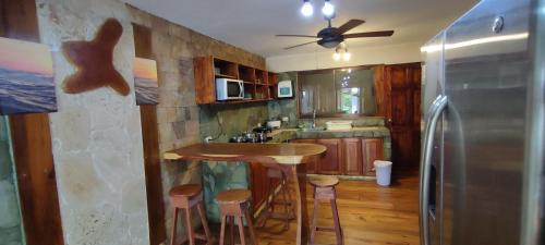 a kitchen with a bar with stools and a refrigerator at Apartotel VILLA ALTA TAMARINDO in Tamarindo