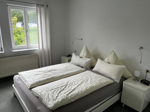 a bedroom with a bed with white sheets and a window at Gästehaus Lena in Mudau