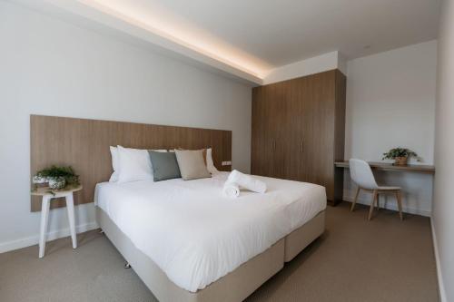 una camera con un grande letto bianco e una scrivania di Beach & Bay Stay Motel a Callala Beach