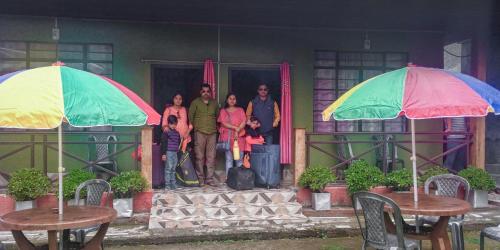 a group of people standing outside of a house with umbrellas at 3 Sisters' Homestay in Ravangla