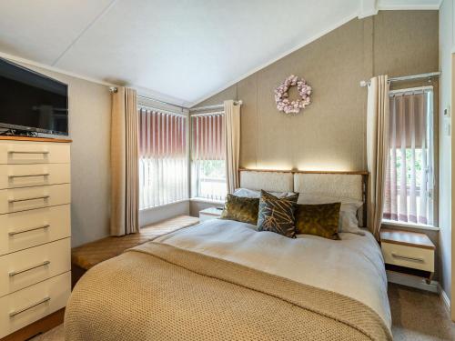 a bedroom with a bed and a tv and windows at Links Lodge in Grange Over Sands