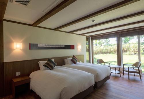 a bedroom with two beds and a large window at Biei Villa Rubeshibe Hill in Biei