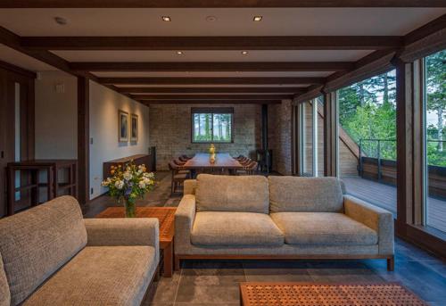 a living room with a couch and a table at Biei Villa Rubeshibe Hill in Biei