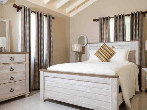 um quarto com uma cama branca e uma cómoda em Home sweet home, Stonebrook Manor, Trelawny. em Falmouth