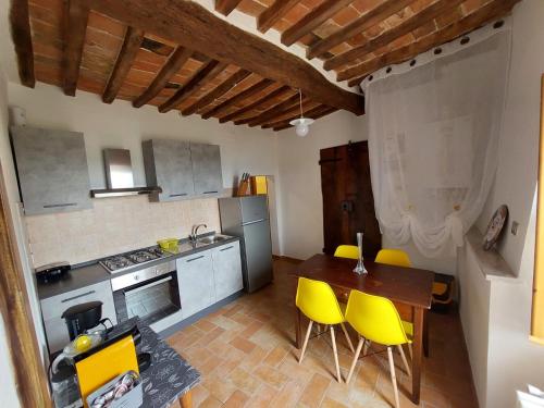 una cucina con tavolo in legno e sedie gialle di Appartamento Athena a Montepulciano
