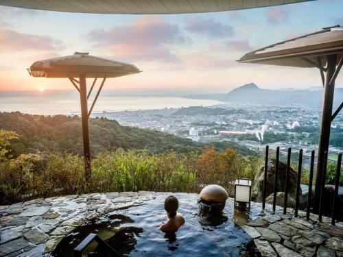 a child in a bath tub with a view of a city at ANA InterContinental Beppu Resort & Spa by IHG in Beppu