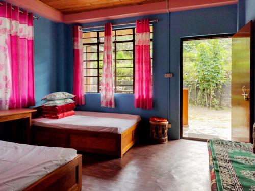 a bedroom with a bed and a window with pink curtains at 3 Sisters' Homestay in Ravangla