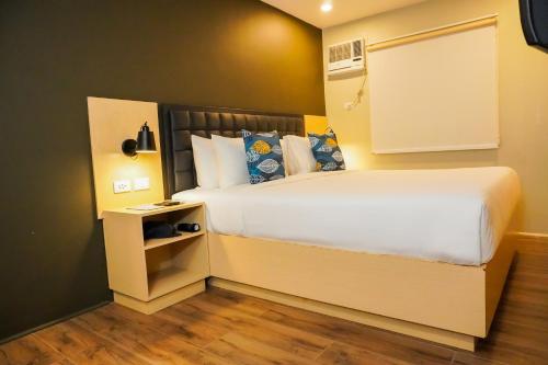a bedroom with a large white bed and a night stand at Kommons by Kamino in Boracay