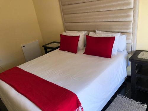 a bedroom with a white bed with red pillows at Phokela Guest House in Mokopane