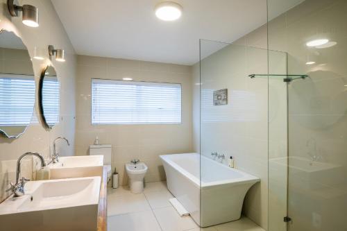 a bathroom with a tub and a sink and a toilet at Dune Beach House in Wilderness