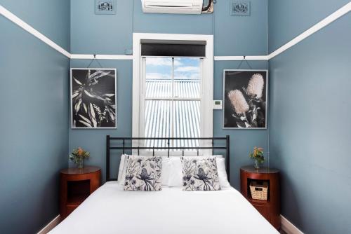 Dormitorio azul con cama y ventana en The Paragon Hotel, en Mudgee