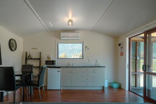 a kitchen with a counter and a table and a window at Te Awa Cottages in Franz Josef