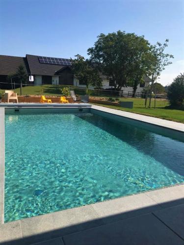 a swimming pool with blue water in front of a house at Pension Kramerhof in Taufkirchen
