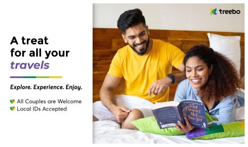 Un uomo e una donna seduti su un letto a leggere libri di Treebo Trend Address Inn a Hyderabad