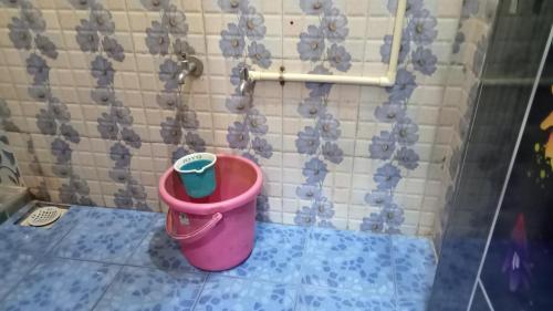 a pink trash can in the corner of a bathroom at Shree Yatri Niwas in Kolhapur