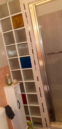a bathroom with a shower with empty shelves on the wall at Appartement confortable avec vue sur le jardin - Le Robert in Le Robert
