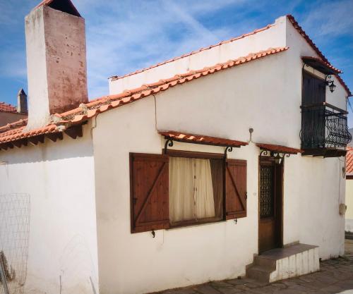 a white house with wooden doors and a tower at Agrampeli in Limenaria
