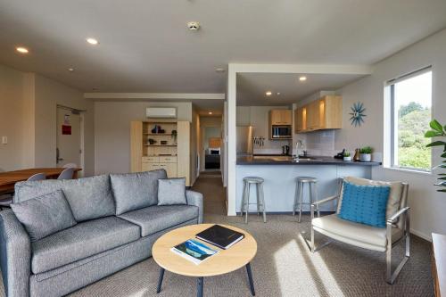 a living room with a couch and a table and a kitchen at Waves on the Esplanade in Kaikoura