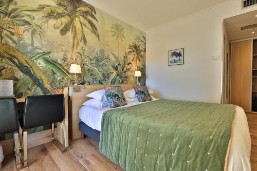 a bedroom with a green bed with a tropical wallpaper at Le Petit Prince in Sainte-Maxime
