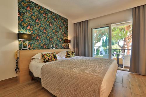 a bedroom with a large bed with a painting on the wall at Le Petit Prince in Sainte-Maxime