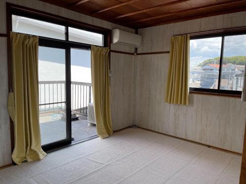 a room with two large windows and a balcony at Guest house Nagi - Vacation STAY 21489v in Kanayama