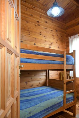 a bedroom with two bunk beds in a wooden wall at El Llano de los Conejos Serranía de Cuenca in Cañamares