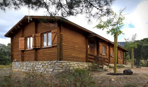 a wooden house with a stone wall at El Llano de los Conejos Serranía de Cuenca in Cañamares