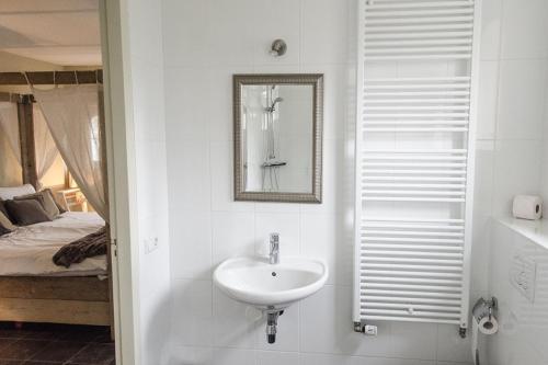 a bathroom with a sink and a mirror and a bed at B&B de Remketting in Slijk-Ewijk