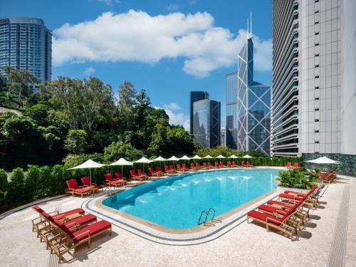 a swimming pool with lounge chairs and a city skyline at Island Shangri-La, Hong Kong in Hong Kong
