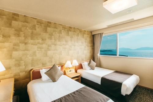 a hotel room with two beds and a window at KAMENOI HOTEL Genkainada in Kitakyushu