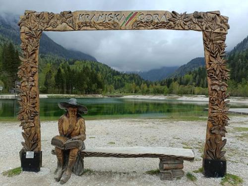 a statue of a man sitting on a bench next to a lake at Apartments Blažič in Kranjska Gora