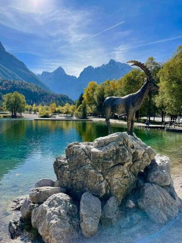 a statue of a goat standing on a rock near a lake at Apartments Blažič in Kranjska Gora