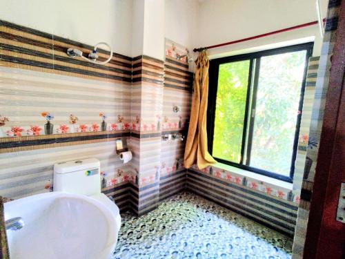 baño con bañera, aseo y ventana en Jungle Heaven Hotel and Cottage en Bhurkīā
