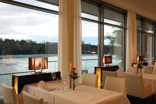 a restaurant with white tables and chairs and a large window at Park-Hotel am Rhein - Gesundheitshotel und Residenzen in Rheinfelden